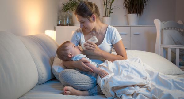 A woman feeding a baby a bottle before bed