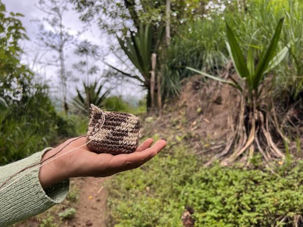 Silvia Vetancourt holds out a coin purse she is crocheting from cabuya fiber on the path to Plaza Gutierrez, Ecuador. Photo by Liz Kimbrough.